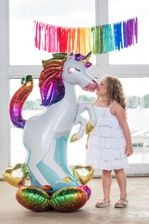 Girl playing with large unicorn Airloonz balloon at birthday party