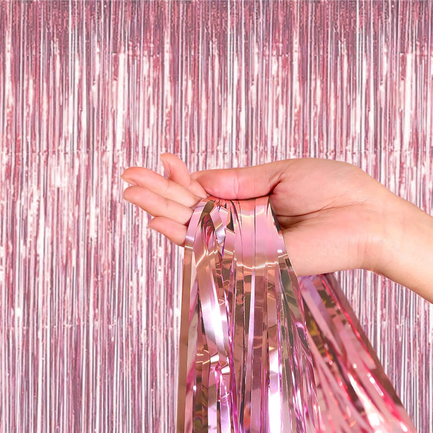 “Hand holding rose gold foil fringe curtain backdrop”