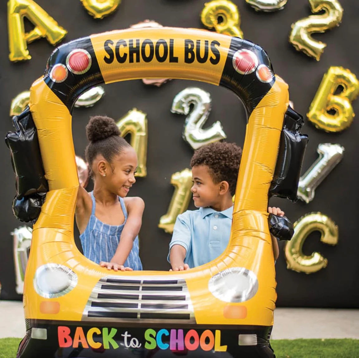 Children posing inside yellow school bus selfie balloon – classroom photo prop