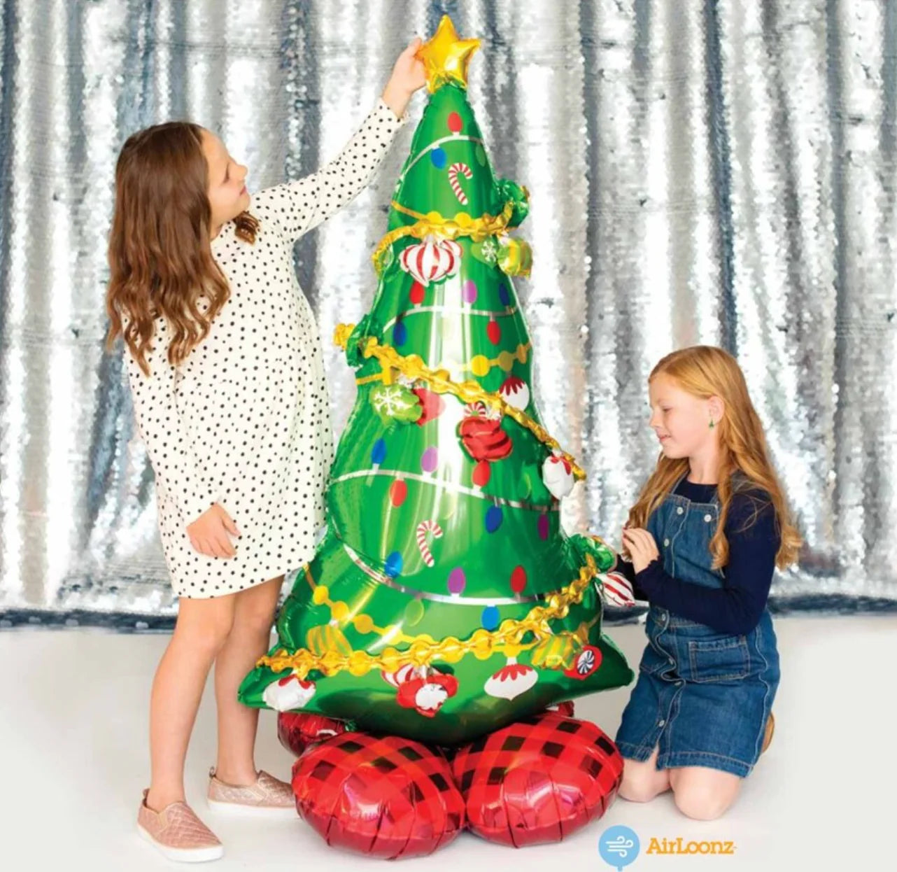 "Kids admiring AirLoonz Christmas tree balloon indoors with winter background"