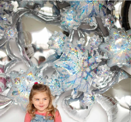 Snowflake Cluster Prism balloon used in winter-themed decor with child