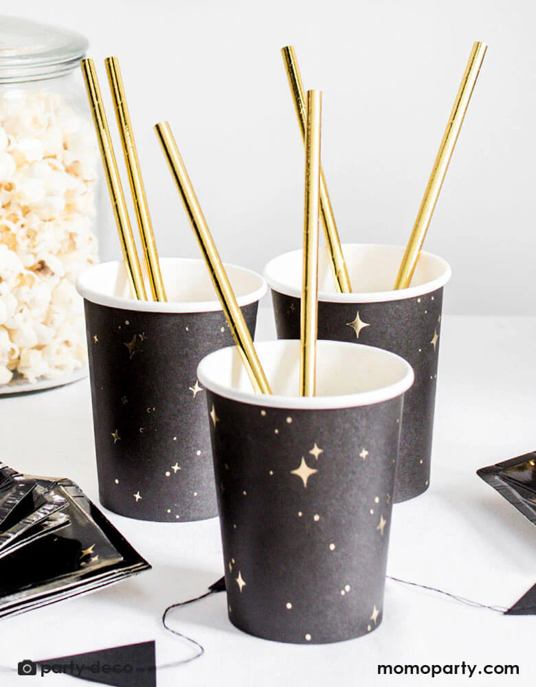 Party drink station with black paper cups and golden straws
