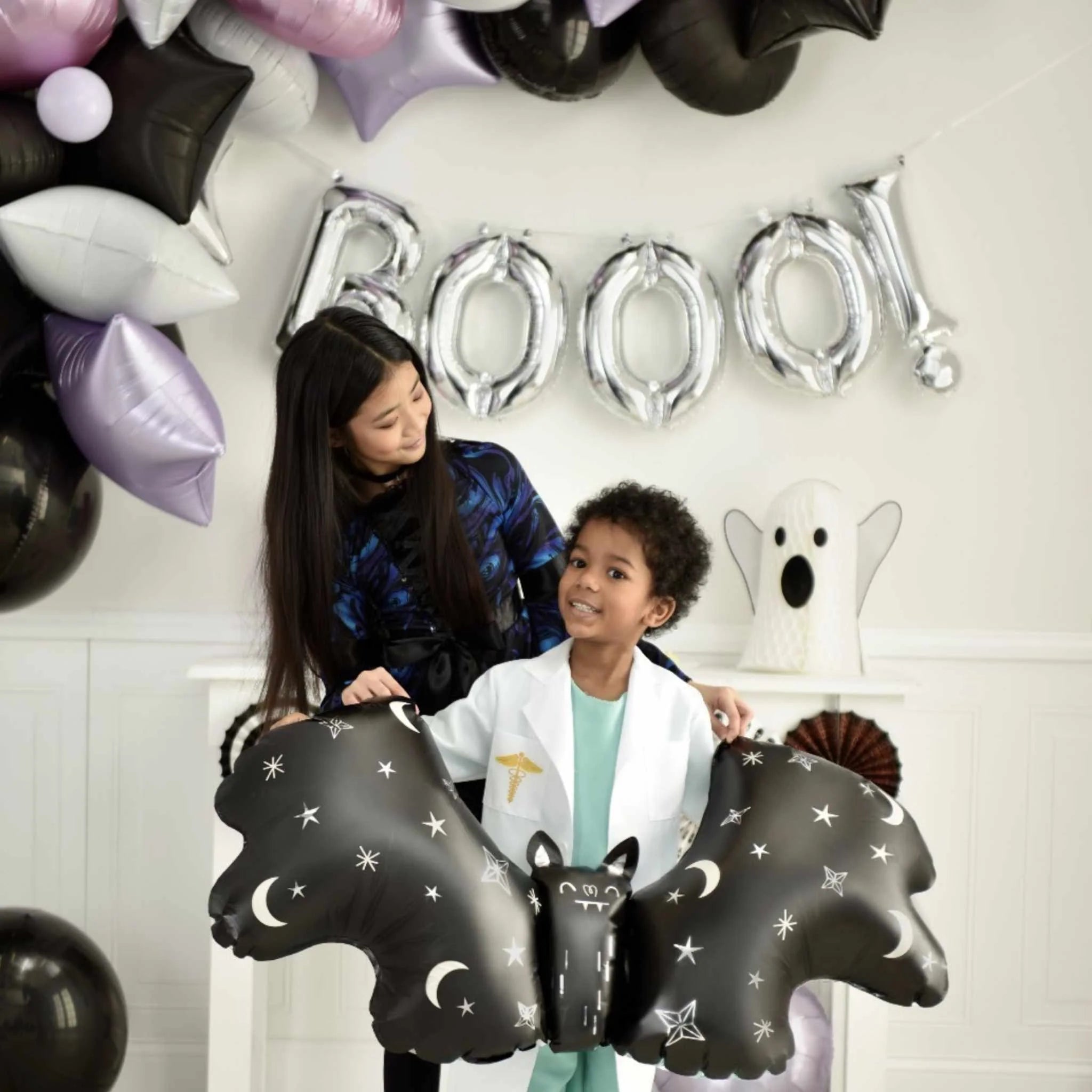 Children posing with Satin Bat Attack balloon in Halloween setup