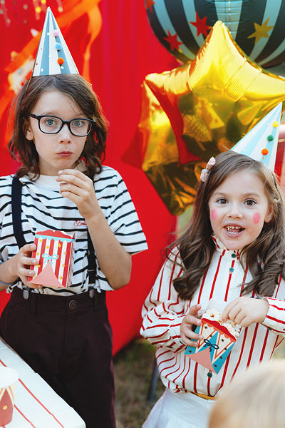 Children holding circus snack boxes at a themed party