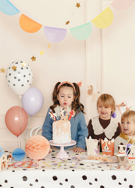 Pastel party table setup with colorful hanging garlands