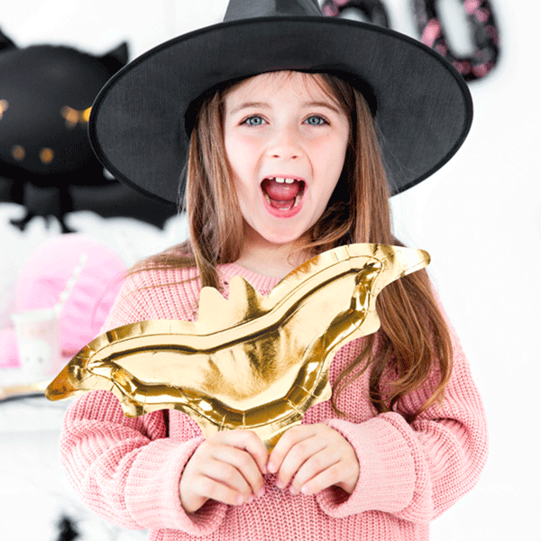 "Girl in witch costume holding gold bat plates"