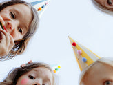 Group of kids celebrating outdoors with colorful party hats