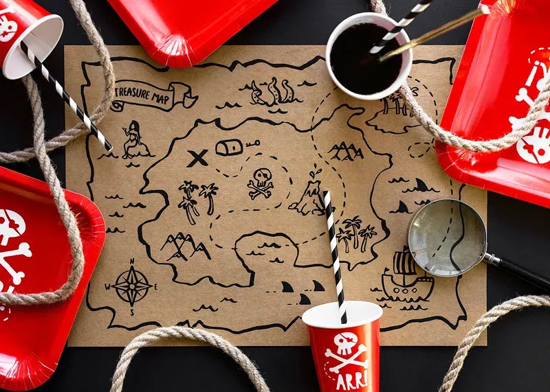 “Flat lay of pirate party cups, plates, and treasure map decor”